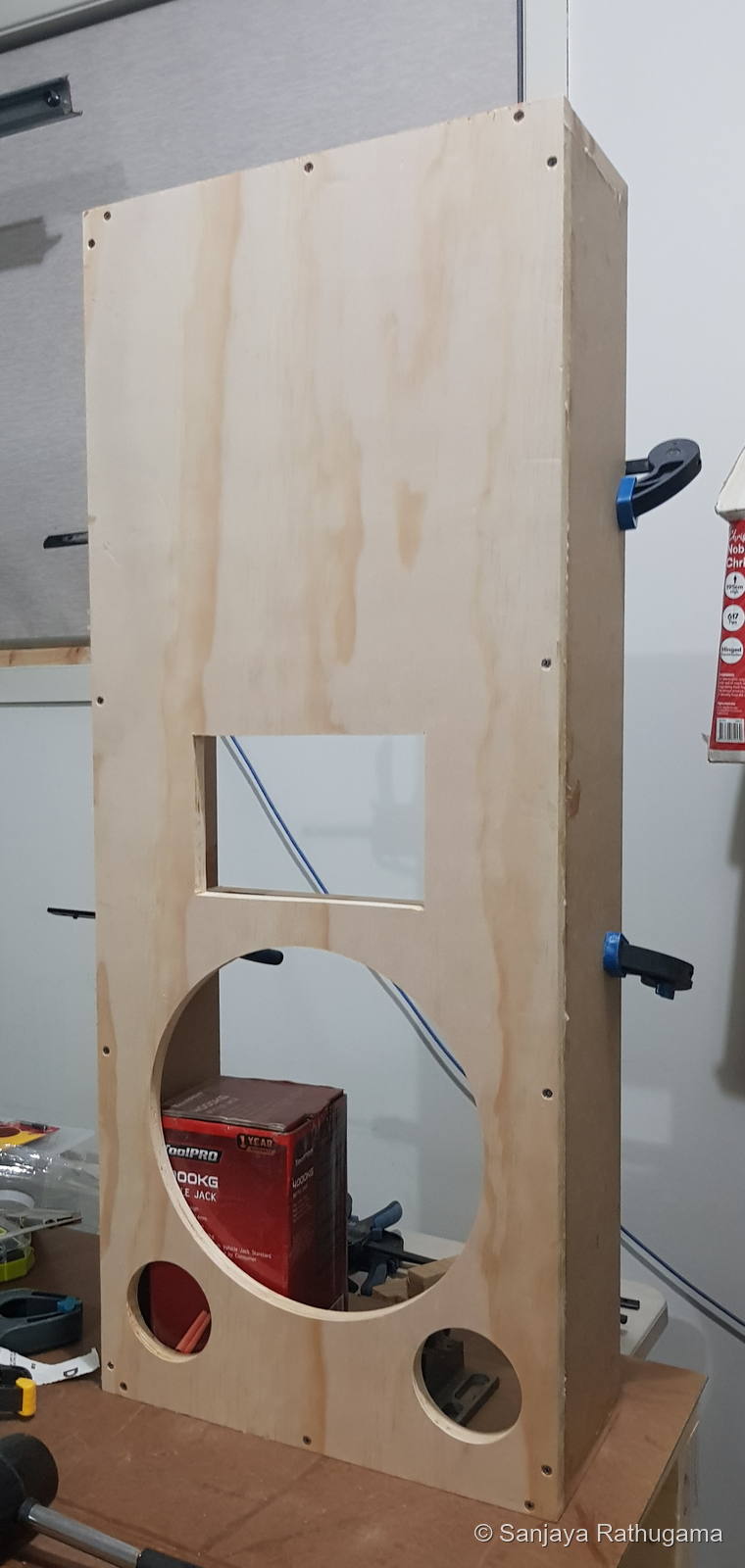 Bare plywood front baffle fitted to the shallow cabinet, with horn, woofer and two port openings