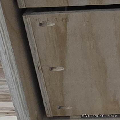 Close-up of three elongated pocket holes near the left edge of a plywood drawer-box front, with screw heads recessed inside
